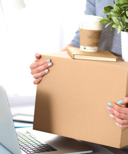 A Woman Carrying Packing Boxes And Moving Office — Furniture Removal in Coffs Harbour, NSW